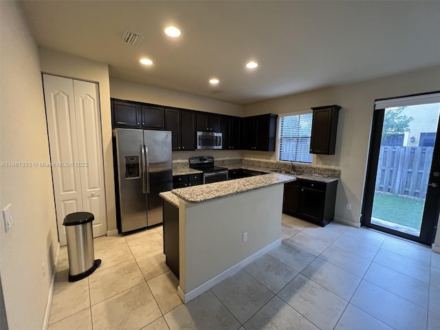 kitchen with a kitchen island, plenty of natural light, appliances with stainless steel finishes, and light tile floors