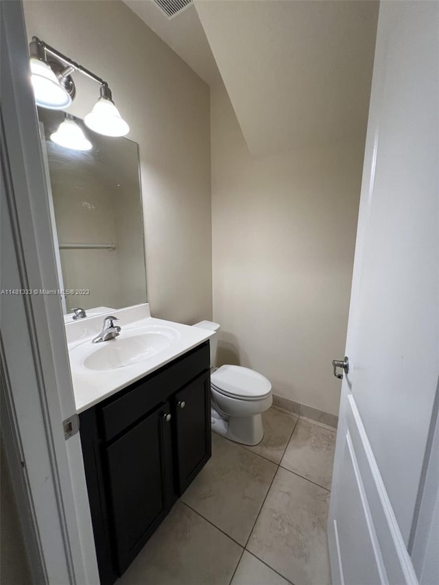 bathroom featuring tile floors, vanity, lofted ceiling, and toilet