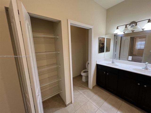 bathroom featuring tile flooring, large vanity, toilet, and dual sinks