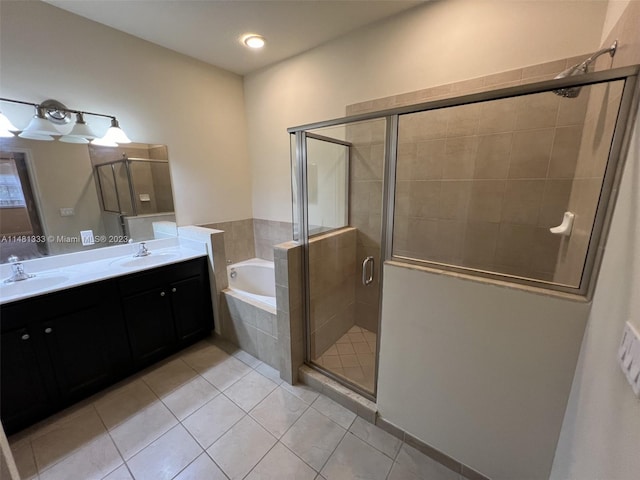 bathroom with vanity with extensive cabinet space, double sink, tile floors, and separate shower and tub