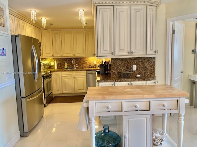 kitchen with sink, light tile floors, butcher block countertops, stainless steel appliances, and tasteful backsplash