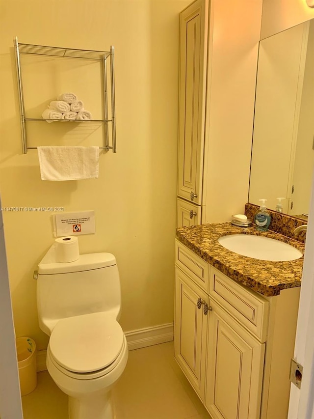 bathroom featuring toilet, vanity, and tile flooring