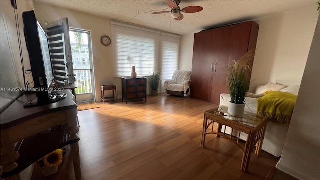 living area with a textured ceiling, light hardwood / wood-style floors, and ceiling fan