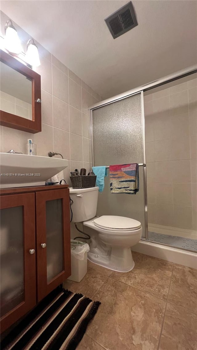 bathroom featuring an enclosed shower, vanity, tile walls, tile floors, and toilet