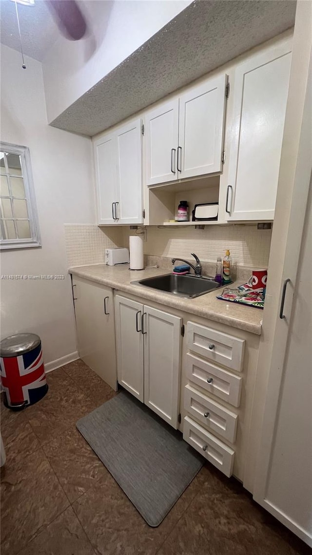 kitchen featuring white cabinetry, dark tile flooring, tasteful backsplash, and sink