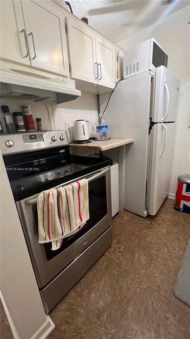 kitchen with white fridge, a textured ceiling, stainless steel electric stove, white cabinetry, and dark tile floors