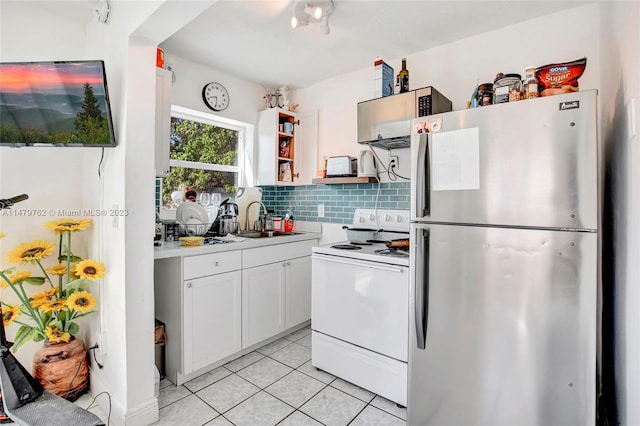 kitchen with white electric range, light tile floors, tasteful backsplash, white cabinetry, and stainless steel refrigerator