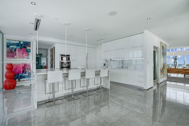 kitchen with stainless steel double oven, white cabinets, a breakfast bar area, and a kitchen island