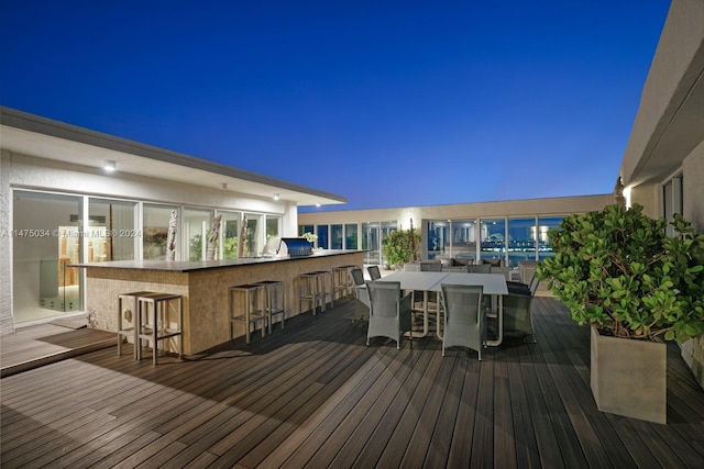 deck at night featuring a grill and a bar