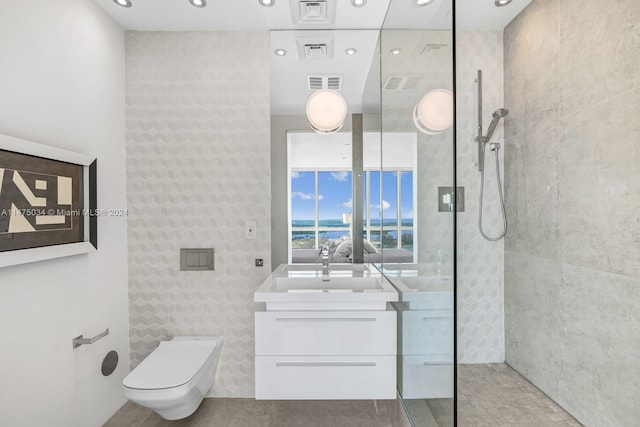 bathroom featuring a water view, tile walls, tile floors, toilet, and vanity