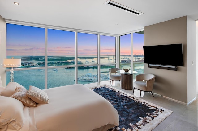 bedroom with tile flooring, a water view, and expansive windows