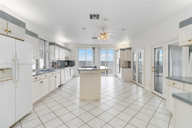 kitchen with a kitchen island, ceiling fan, light tile patterned floors, sink, and white appliances