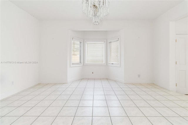 empty room featuring light tile patterned floors and a chandelier