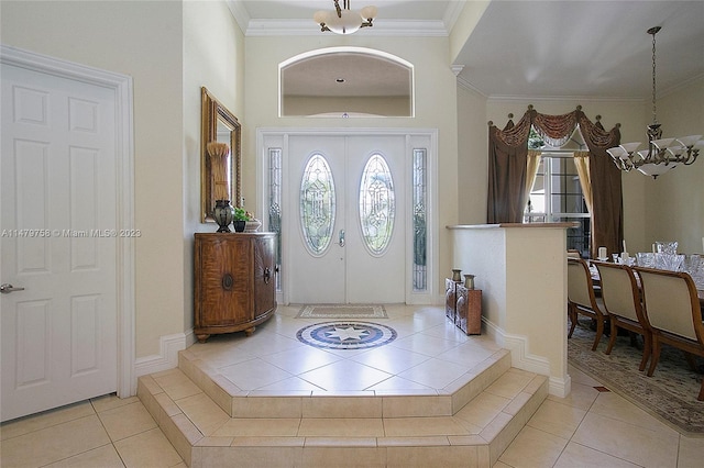 entryway featuring an inviting chandelier, ornamental molding, a healthy amount of sunlight, and light tile floors