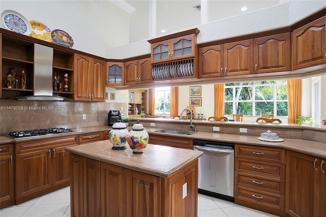 kitchen featuring stainless steel appliances, a kitchen island, wall chimney range hood, light tile flooring, and sink