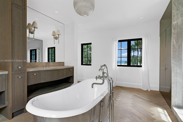 bathroom featuring a tub, vanity, and parquet flooring