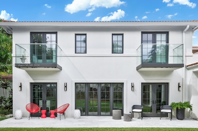 rear view of house featuring a balcony, a patio, and french doors