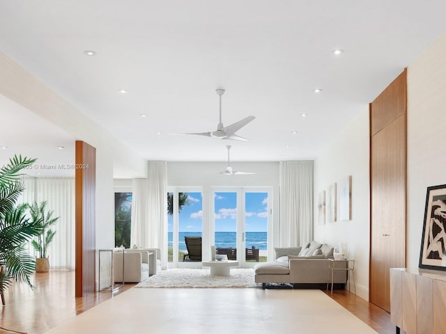 living room featuring a water view, ceiling fan, and light hardwood / wood-style floors