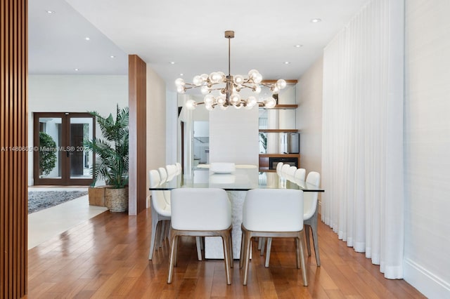 dining area with a notable chandelier, french doors, and light wood-type flooring