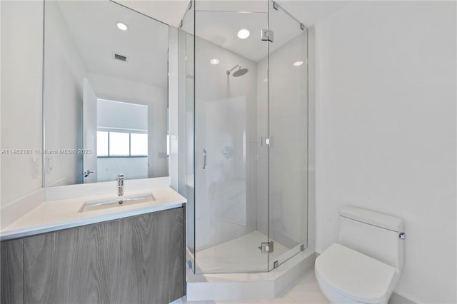 bathroom featuring toilet, tile floors, a shower with shower door, and vanity with extensive cabinet space