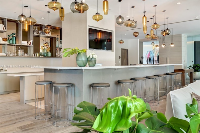 kitchen with pendant lighting, a breakfast bar, and light hardwood / wood-style flooring