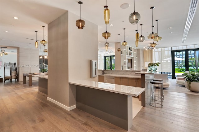 bar featuring light stone countertops, decorative light fixtures, and light hardwood / wood-style flooring