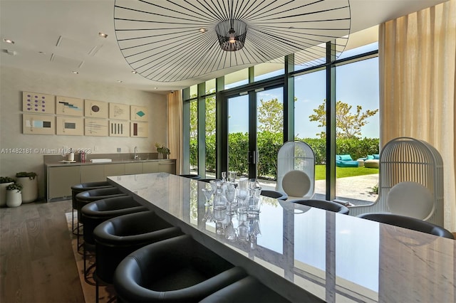 interior space featuring a wealth of natural light, dark hardwood / wood-style floors, light stone counters, and a wall of windows