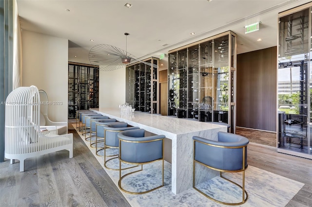 bar with hanging light fixtures, light hardwood / wood-style floors, and light stone counters