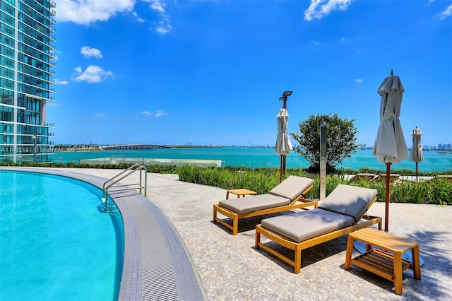 view of pool featuring a water view and a patio