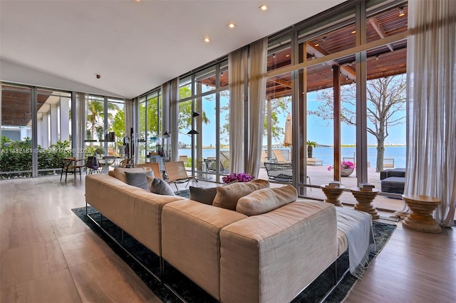 living room with hardwood / wood-style floors, a water view, and a wall of windows