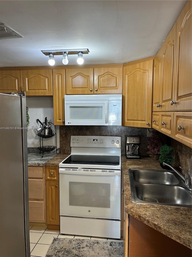 kitchen with white appliances, sink, light tile floors, rail lighting, and tasteful backsplash