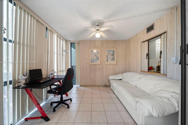 tiled office space featuring ceiling fan, wooden walls, and a textured ceiling