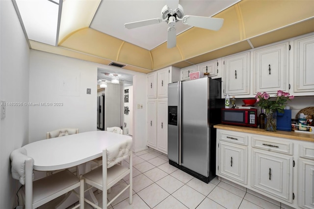 kitchen with light tile patterned flooring, ceiling fan, stainless steel fridge, and white cabinets