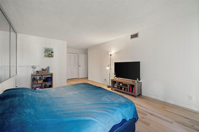 bedroom featuring wood-type flooring, a textured ceiling, and a closet