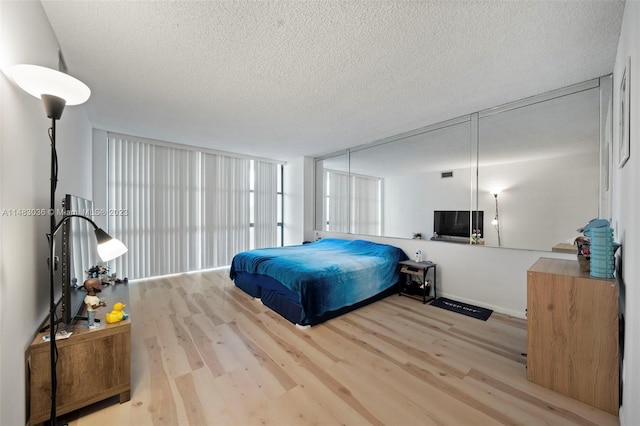 bedroom with a textured ceiling and light hardwood / wood-style flooring