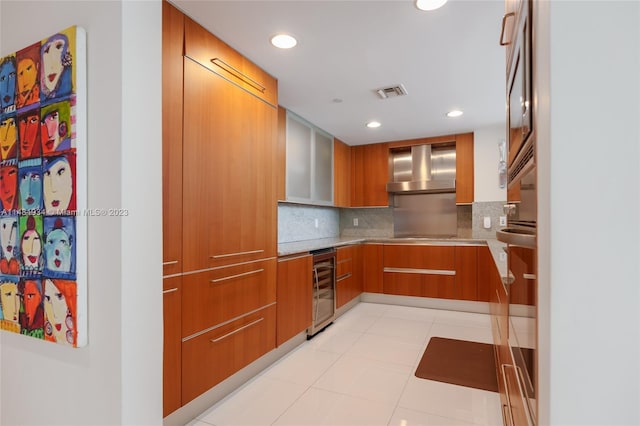 kitchen with wall chimney range hood, tasteful backsplash, light tile floors, and beverage cooler