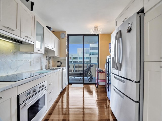 kitchen featuring sink, dark hardwood / wood-style flooring, stainless steel appliances, decorative backsplash, and white cabinets