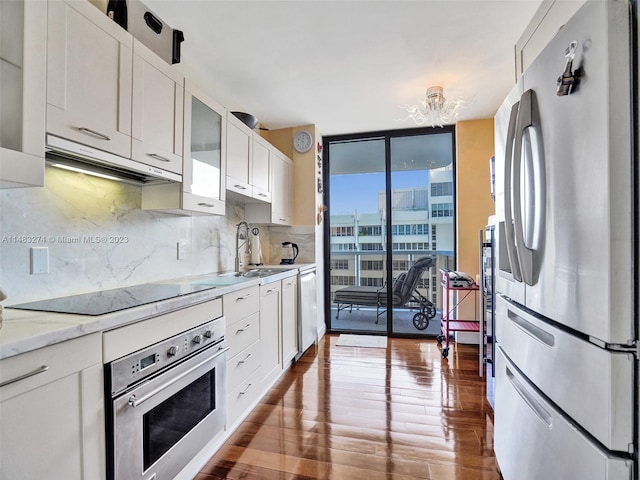 kitchen with tasteful backsplash, sink, white cabinets, stainless steel appliances, and floor to ceiling windows