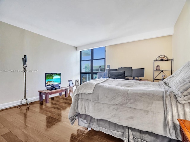 bedroom with floor to ceiling windows and hardwood / wood-style floors