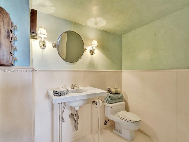 bathroom featuring tile walls, tile patterned floors, and toilet