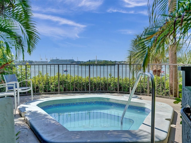 view of pool featuring a water view and an in ground hot tub