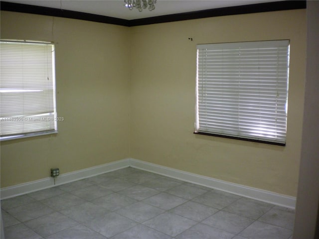 empty room featuring a healthy amount of sunlight, crown molding, and light tile flooring