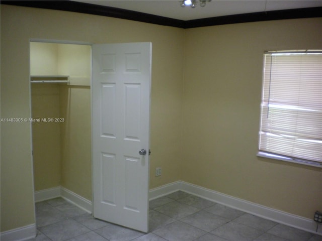 unfurnished bedroom featuring light tile floors, multiple windows, and a closet