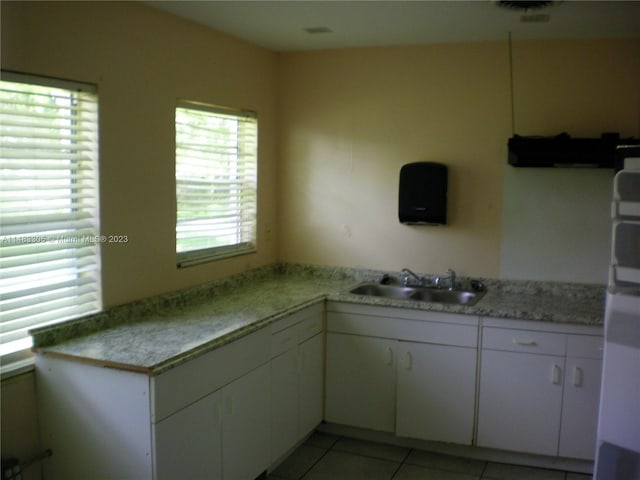 kitchen featuring light tile floors, white cabinetry, and sink