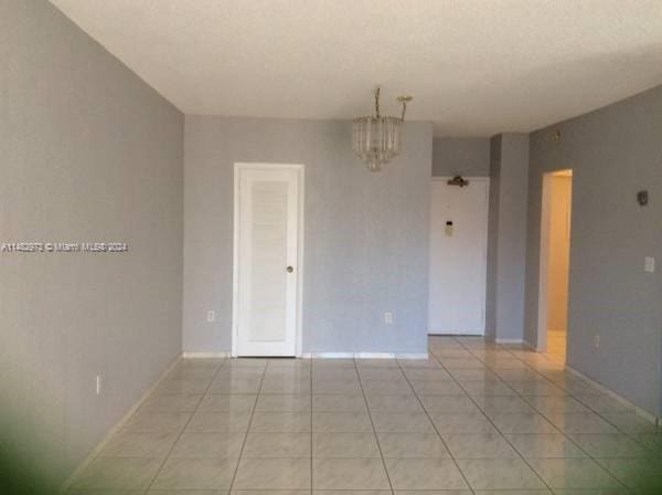 unfurnished room featuring light tile patterned flooring and a chandelier