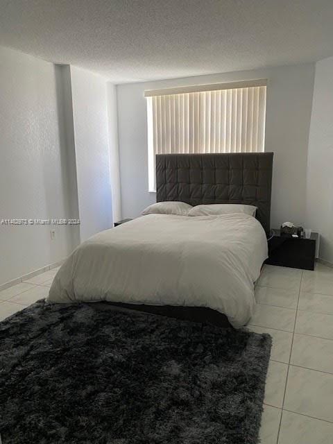 tiled bedroom with multiple windows and a textured ceiling