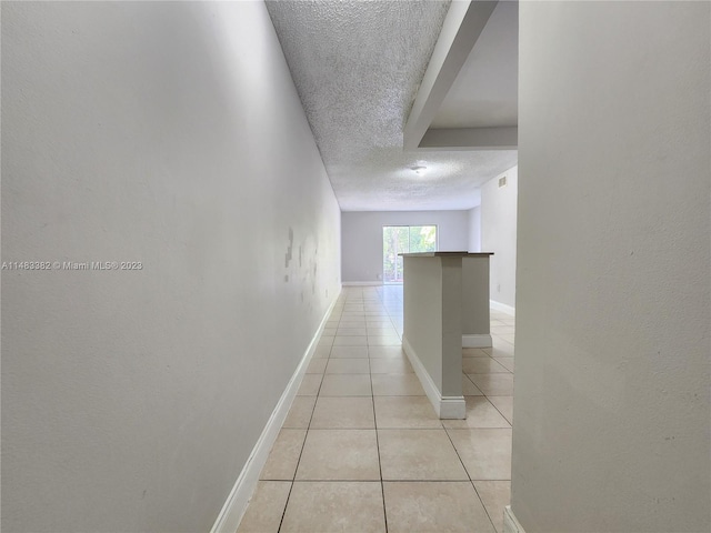 hall featuring light tile floors and a textured ceiling