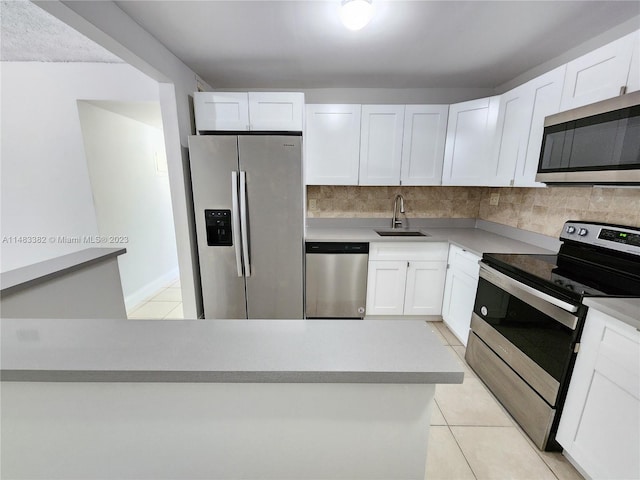 kitchen with sink, appliances with stainless steel finishes, white cabinetry, and light tile flooring