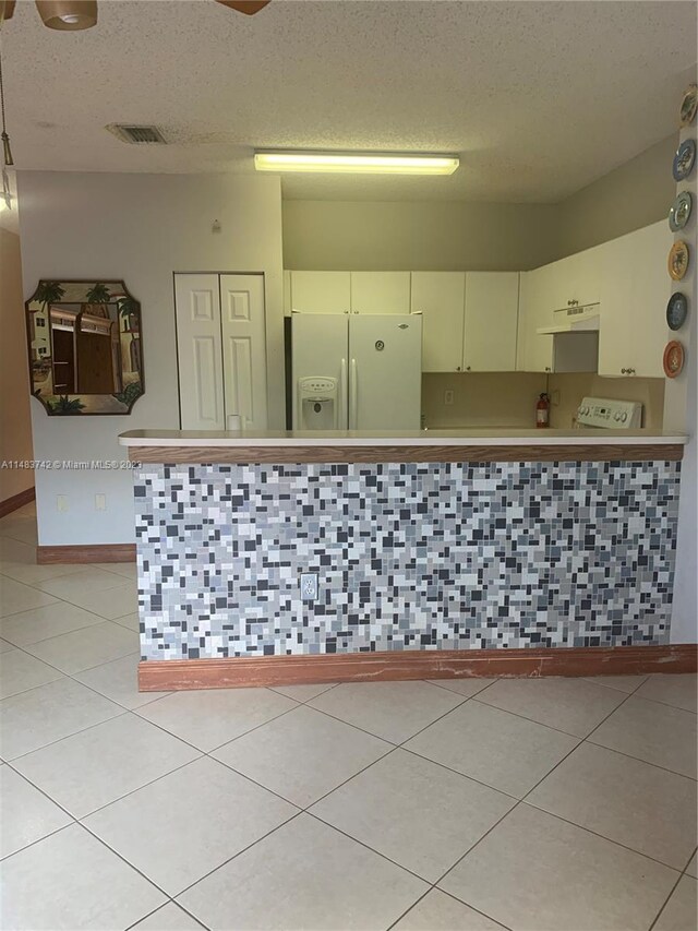 kitchen featuring white fridge with ice dispenser, light tile floors, and a textured ceiling