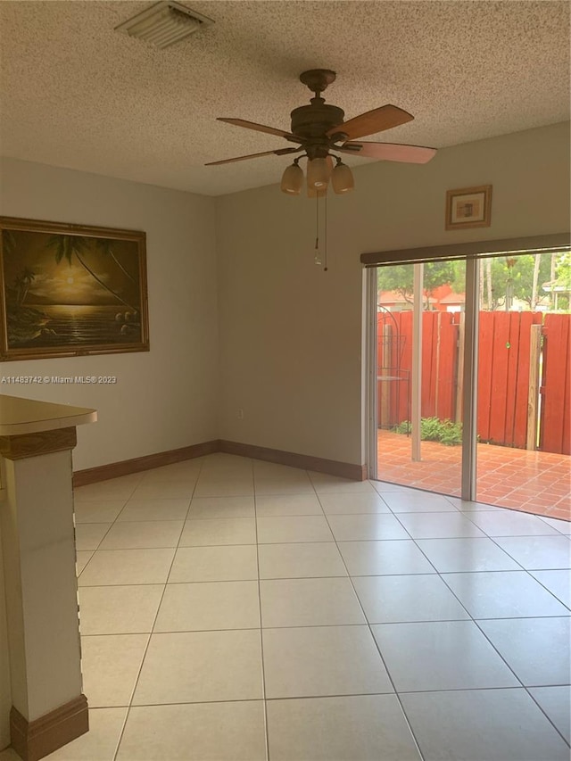 empty room with light tile floors, a textured ceiling, and ceiling fan